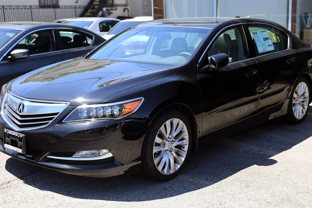 A black 2014 Acura RLX sedan with LED headlights, parked on a sunny lot with a window sticker on the rear side glass