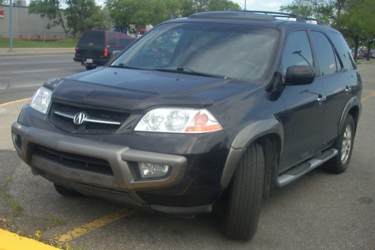 A dark gray first-generation Acura MDX of the 2001-2003 model years parked in a lot in Montreal, Quebec, seen from the front left