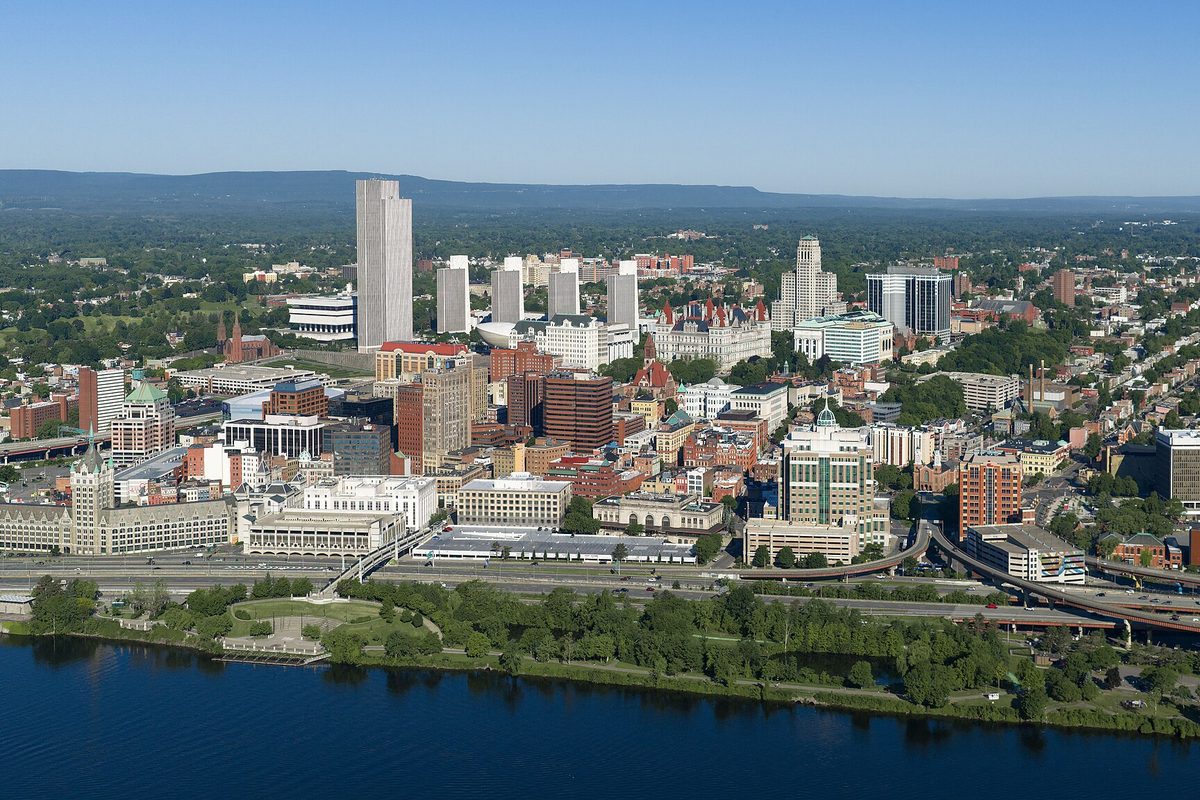 Aerial view of downtown Albany's office towers and state buildings rising above the Hudson River on a clear day