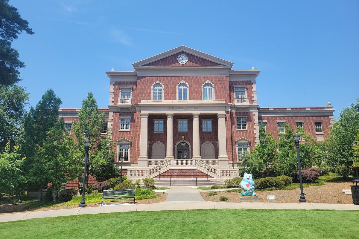 Alpharetta City Hall, a red brick building with white columns and a clock in its pediment, with a painted bear sculpture and lampposts on the lawn