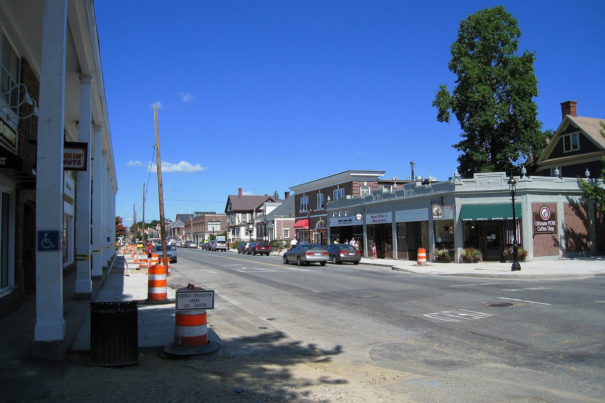 Main Street in downtown Andover on a sunny day, with shops, parked cars, a coffee shop sign and orange construction barrels on the sidewalk