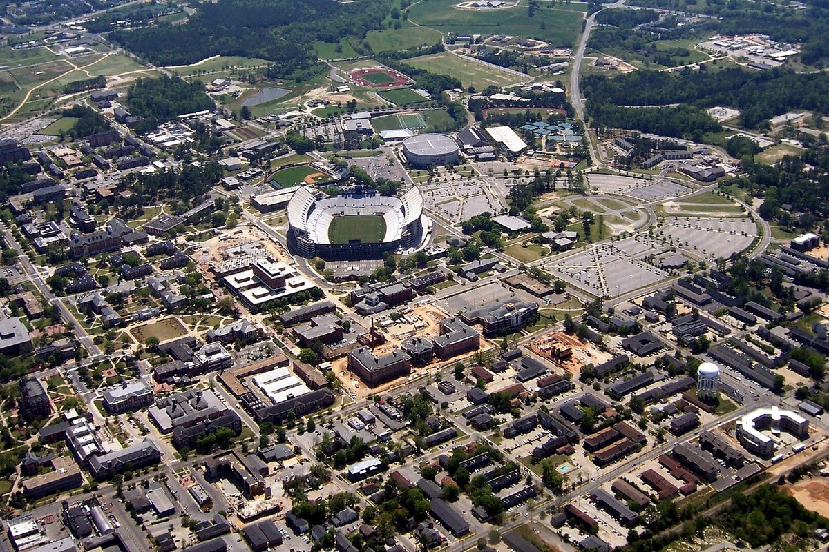 Aerial view of the Auburn University campus, with the football stadium in the middle surrounded by brick buildings, parking lots and trees
