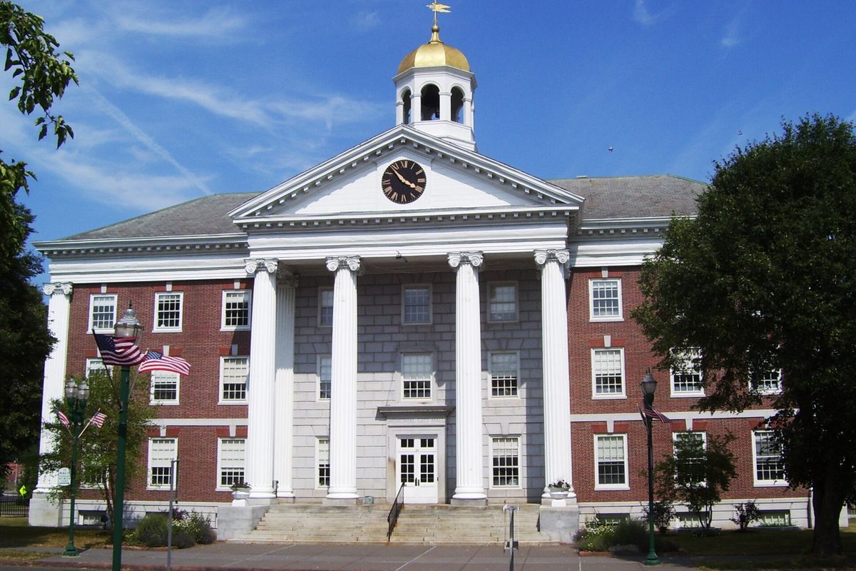 Auburn's Memorial City Hall, a red brick building with tall white columns, a clock in the pediment and a gold-domed cupola, with American flags in front