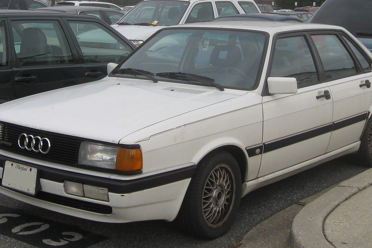 A white Audi 4000CS sedan with black side trim, parked at the edge of a lot