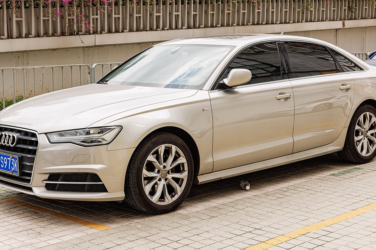 A champagne-colored long-wheelbase Audi A6L sedan of the C7 generation parked on a brick-paved lot