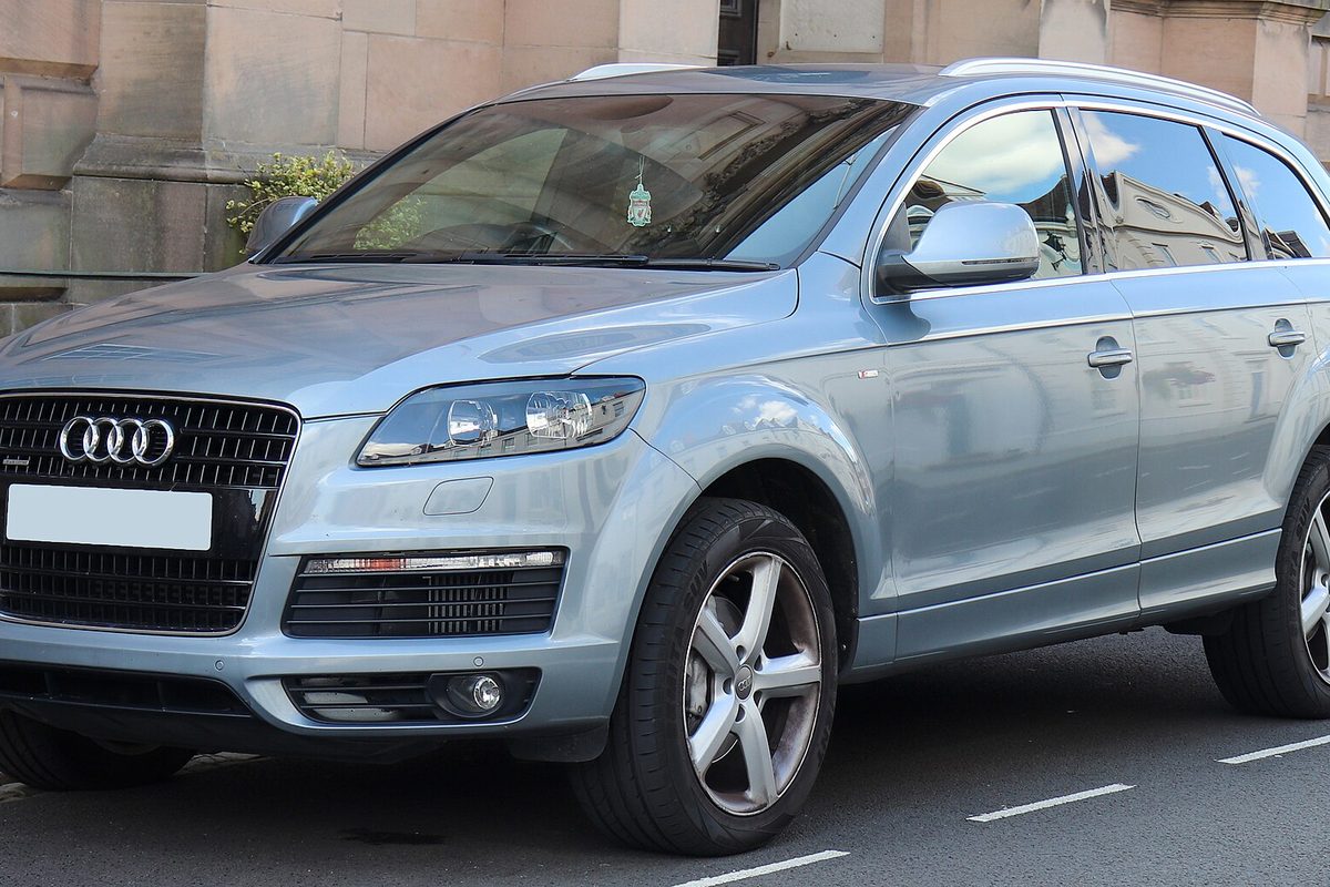 A pale blue-silver first-generation Audi Q7 SUV parked beside a sandstone building