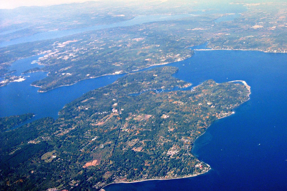 Aerial view of wooded Bainbridge Island and Agate Passage in Puget Sound, with the Olympic Peninsula beyond