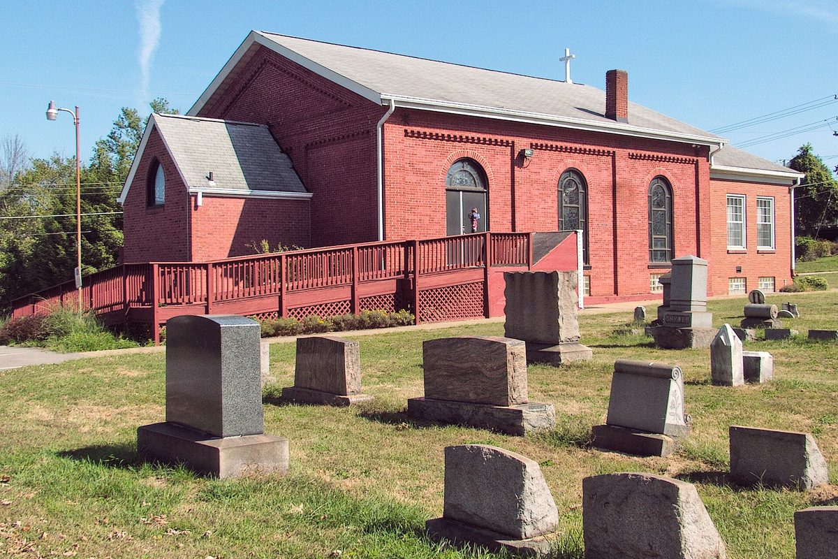North Zion Lutheran Church in Baldwin, a red brick church with arched windows, a wooden ramp and gray headstones on the lawn