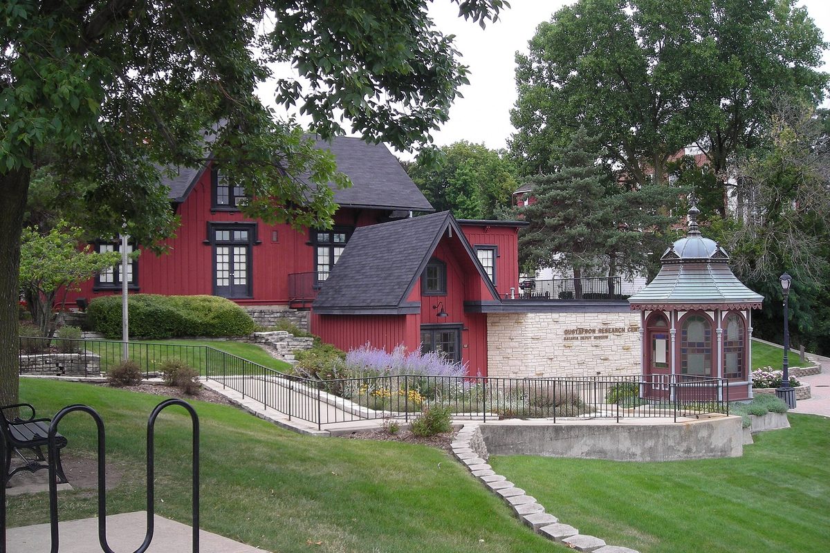 The red wooden Chicago, Burlington and Quincy railroad depot in Batavia, with a stone addition, a green-roofed gazebo, a lawn and lavender in front