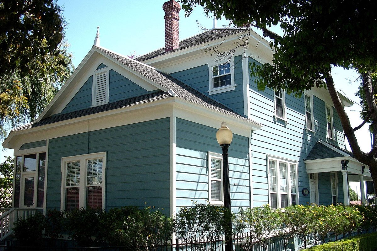 The James George Bell House, a two-story blue-gray clapboard home with white trim, a brick chimney and a street lamp out front