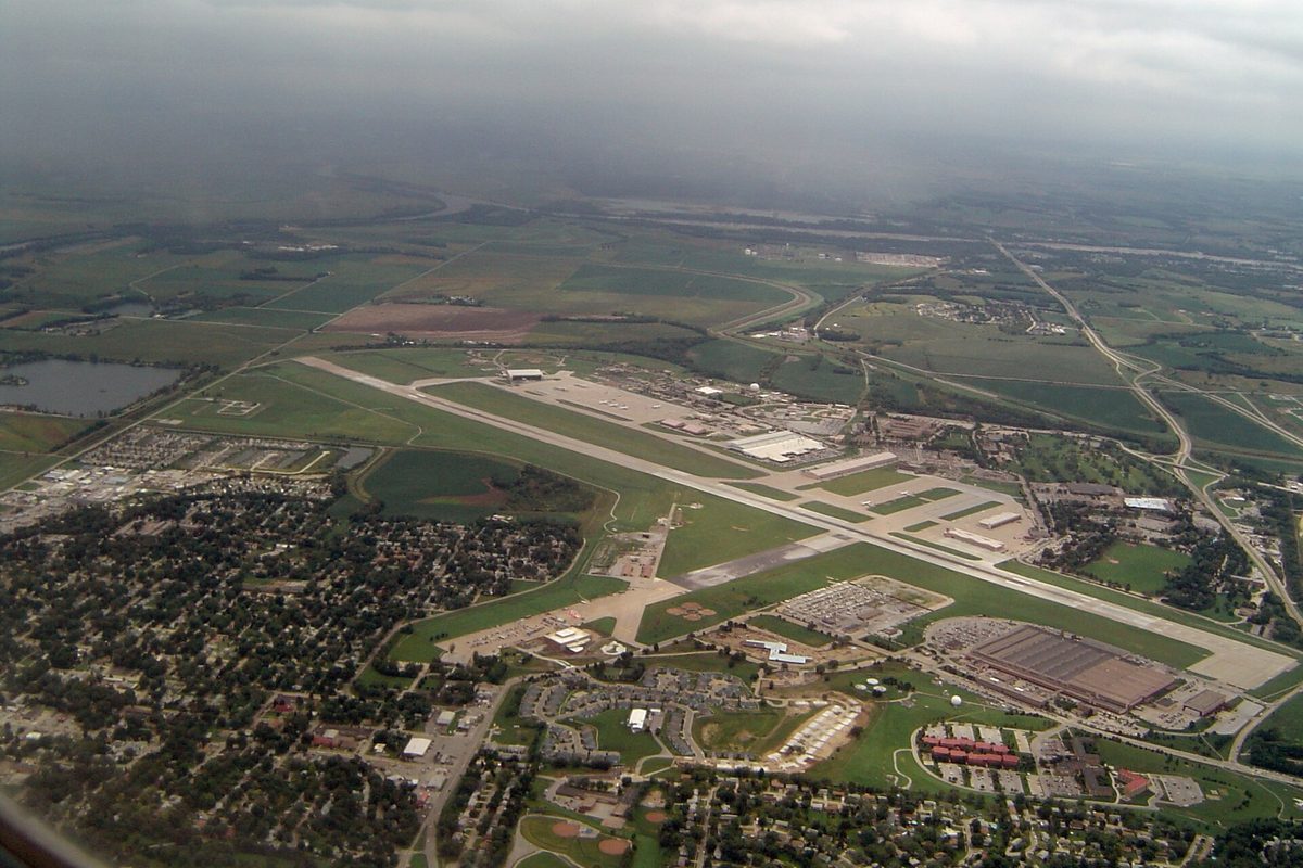 Aerial view of the long runway at Offutt Air Force Base, with neighborhoods in front and farm fields stretching away under low cloud