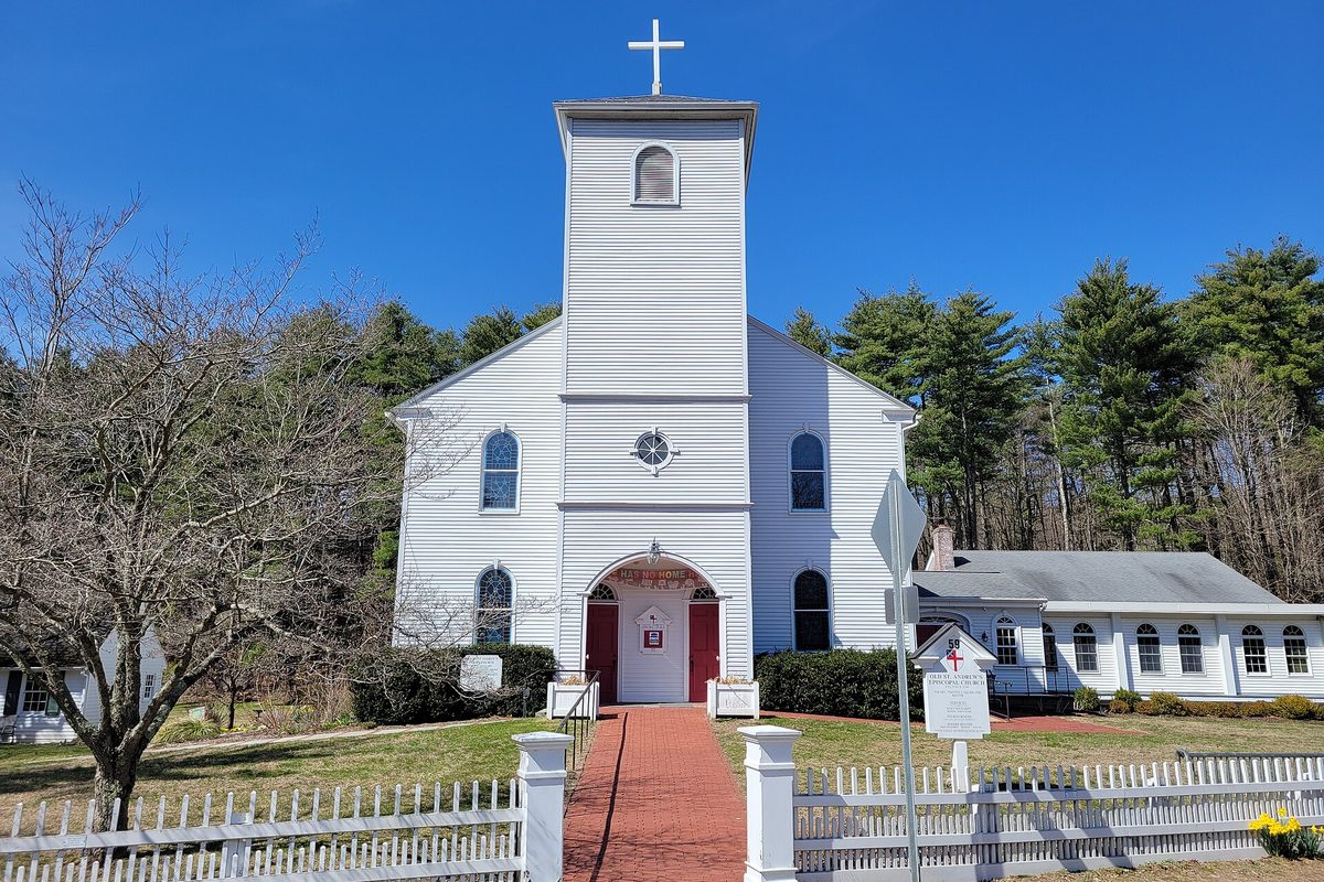 Old St. Andrew's Episcopal Church in North Bloomfield, a white clapboard church with a square bell tower and red doors, behind a white picket fence under a clear blue sky