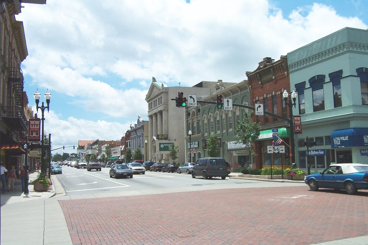 Looking south down Main Street in downtown Bowling Green from Wooster Street, with a brick-paved crosswalk, storefronts and a columned bank building