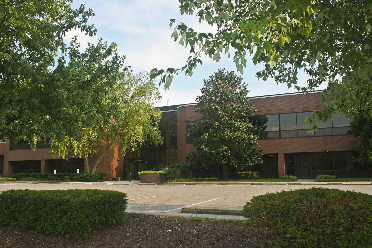 Brentwood Town Hall, a low brick and dark-glass office building half hidden behind green trees and clipped shrubs
