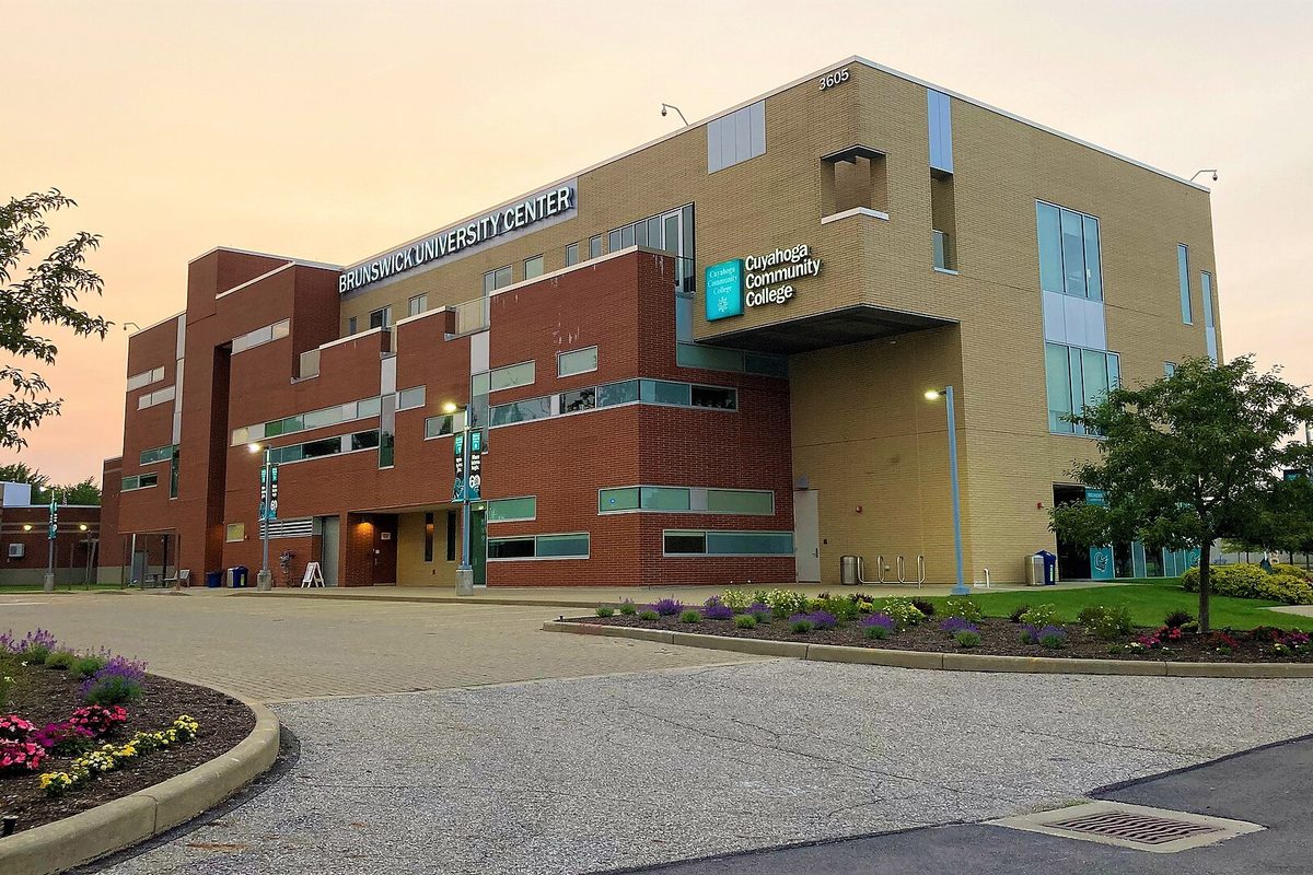 The Brunswick University Center of Cuyahoga Community College, a red brick and tan building with flower beds in front, at dusk