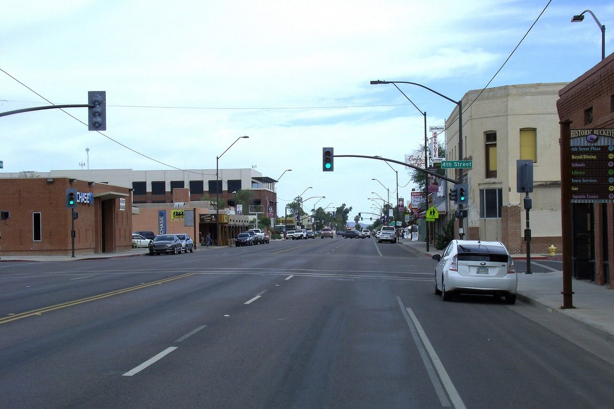 Monroe Avenue in historic downtown Buckeye, a wide street with traffic signals, a 4th Street sign and a historic district directory sign on the corner