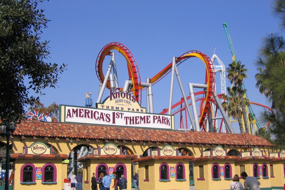 The entrance gate of Knott's Berry Farm in Buena Park, with its America's 1st Theme Park sign, red tile roof and roller coaster loops behind it