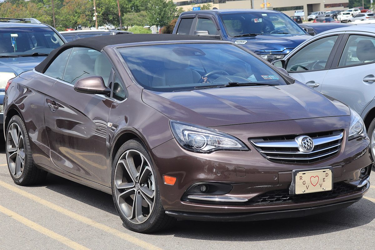 A brown 2016 Buick Cascada convertible with its black soft top up, parked between cars in a lot