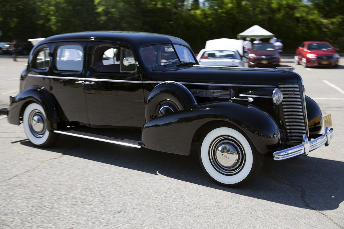 A black vintage Buick Roadmaster four-door sedan with whitewall tires and chrome trim in a parking lot