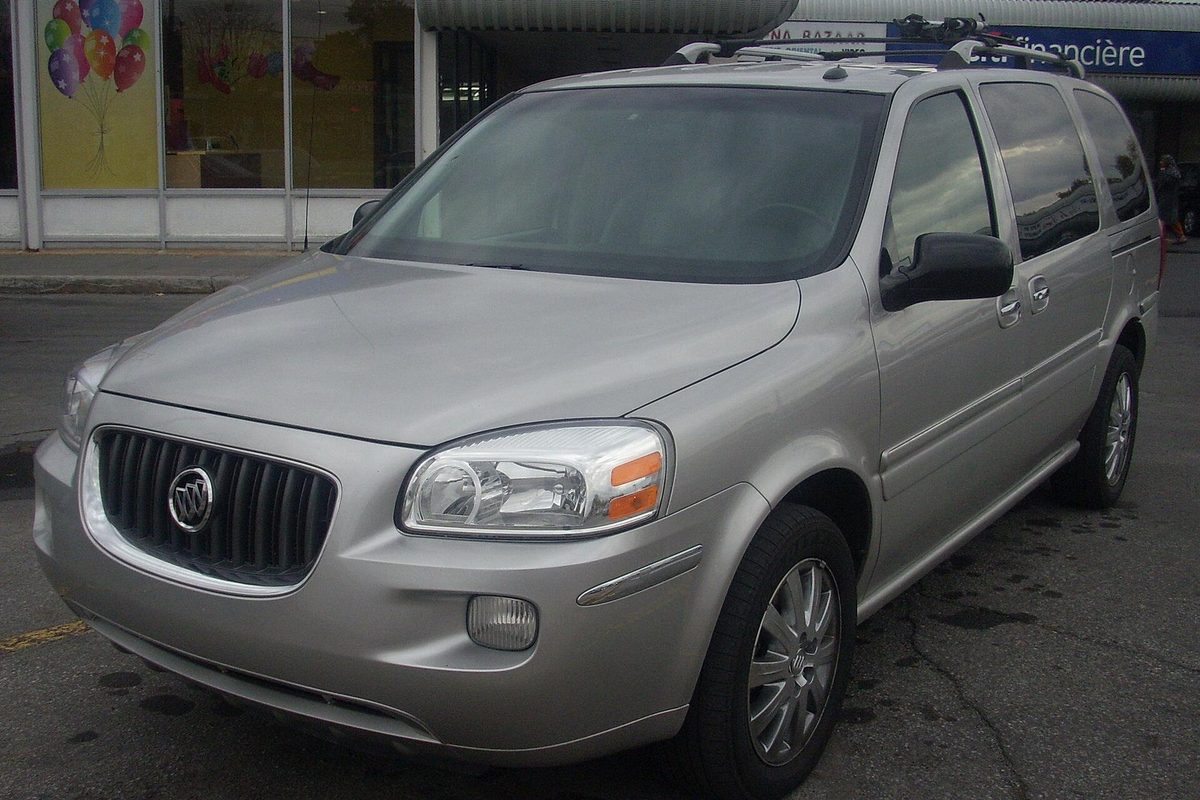 A silver 2005 Buick Terraza minivan parked in front of a storefront with balloons in the window