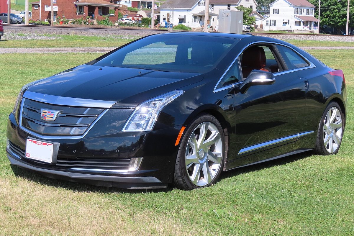 A dark graphite Cadillac ELR coupe, front three-quarter view, parked on a mowed grass field