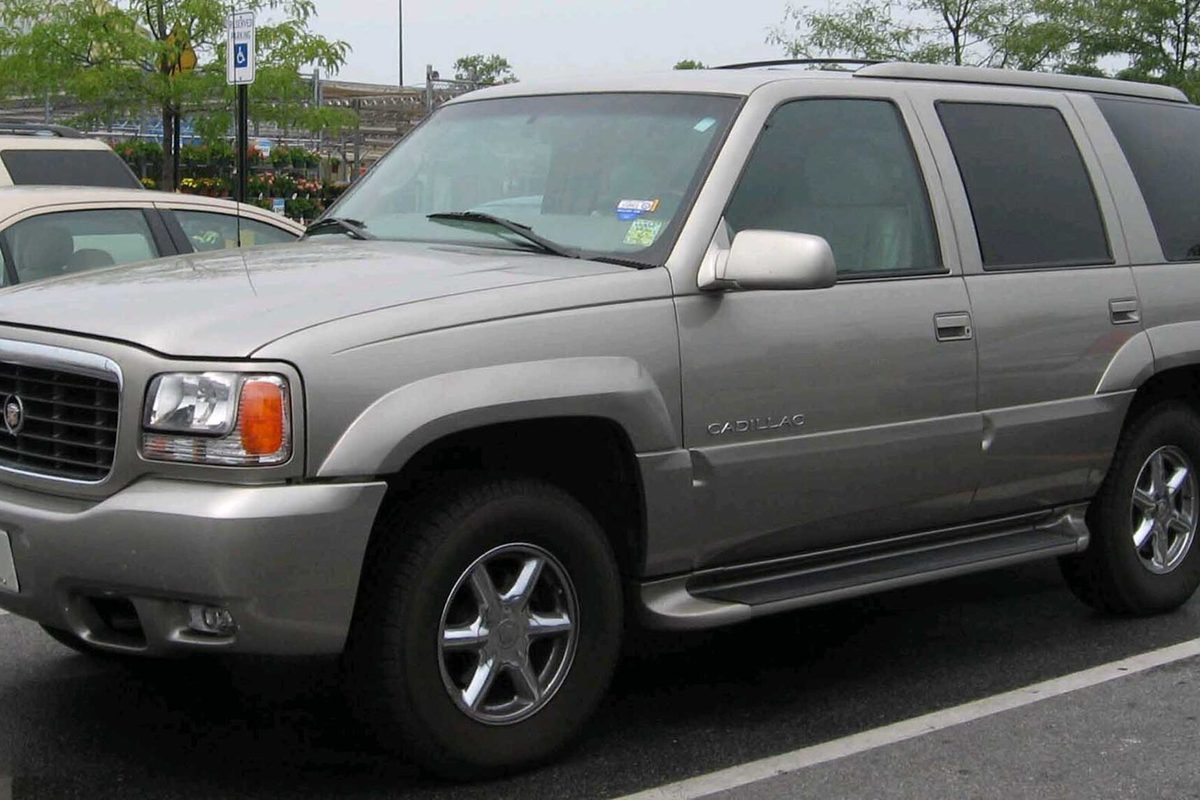 A silver-beige first-generation Cadillac Escalade SUV, a 1999 or 2000 model, parked in a lot in Clinton, Maryland