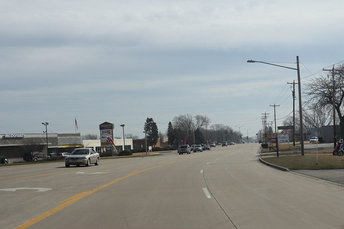 Wisconsin Highway 32 at 4 Mile Road in Caledonia, a wide road with traffic, roadside businesses and power poles under a gray sky