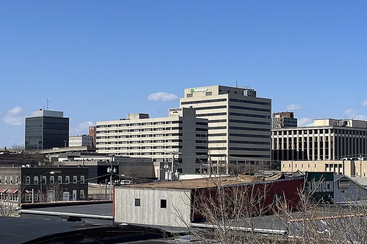 Downtown Canton's office and hotel towers rising behind low brick rooftops and bare trees under a clear blue sky