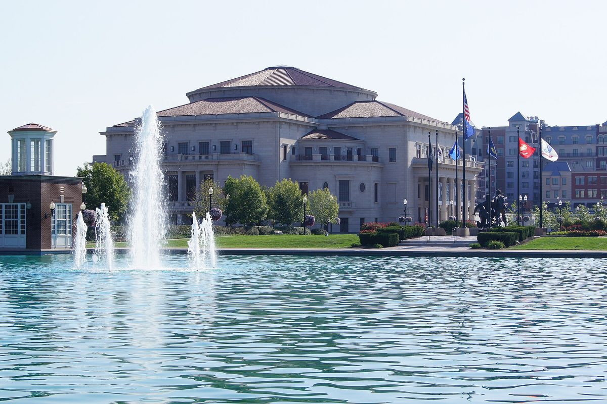 The Palladium concert hall in Carmel, a domed cream-colored building behind a reflecting pool with fountains, flags flying out front