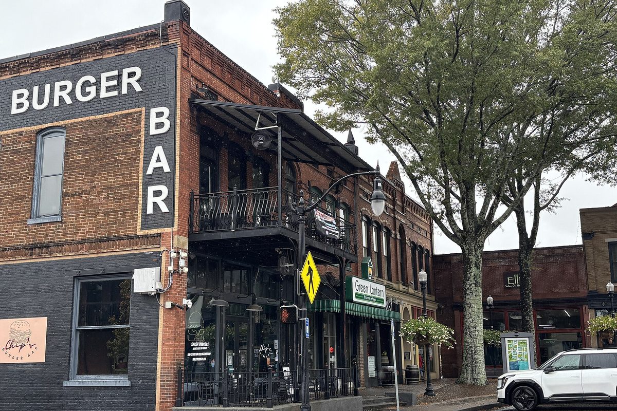 Brick storefronts in downtown Carrollton, with Burger Bar painted on the corner building and wrought-iron balconies along the street