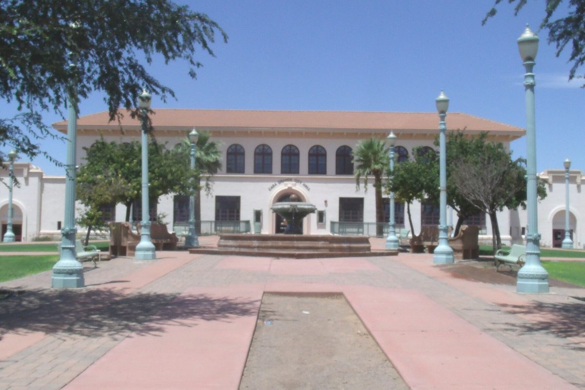 Casa Grande City Hall, the white 1920 former high school with arched windows, behind a fountain and lamp-lined plaza