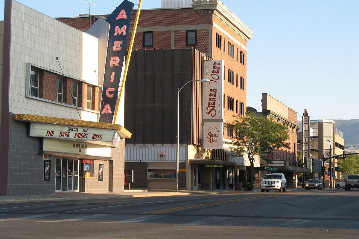 The tall America theater sign and the Sierra West hotel sign on the 100 block of Center Street in downtown Casper, with hills in the distance