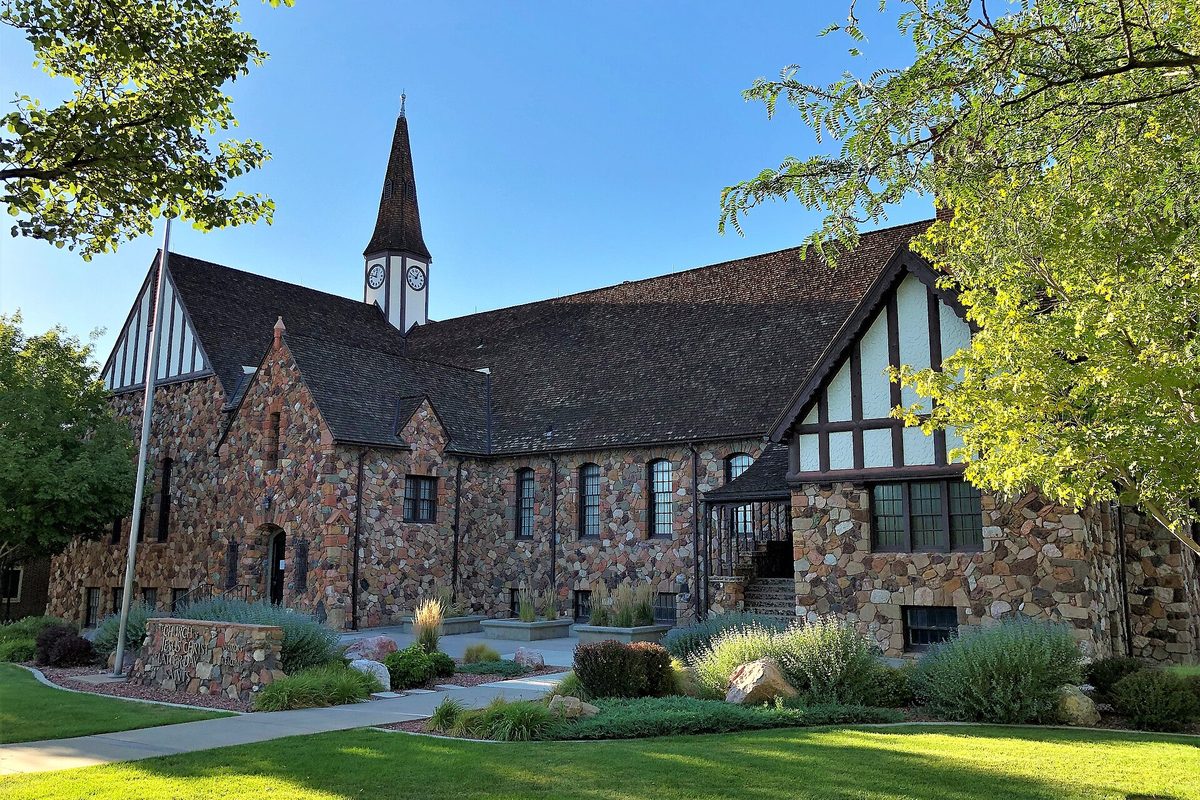 Cedar City's Rock Church, a stone building with a steep dark roof, half-timbered gables and a clock tower, framed by green trees