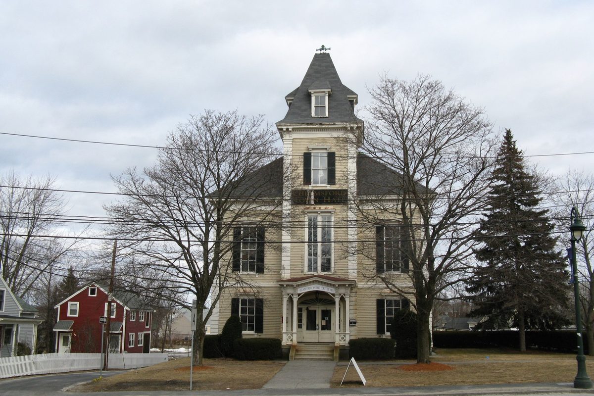 Chelmsford's Old Town Hall, a pale two-storey building with a slate mansard tower, between bare winter trees under a grey sky