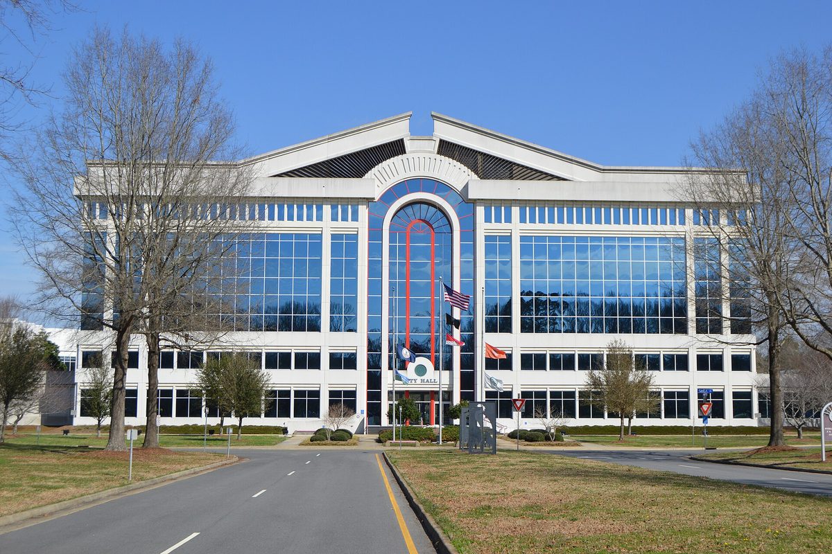 Chesapeake City Hall, a wide glass-fronted building with a tall arched entrance and flags out front, on a clear winter day with bare trees