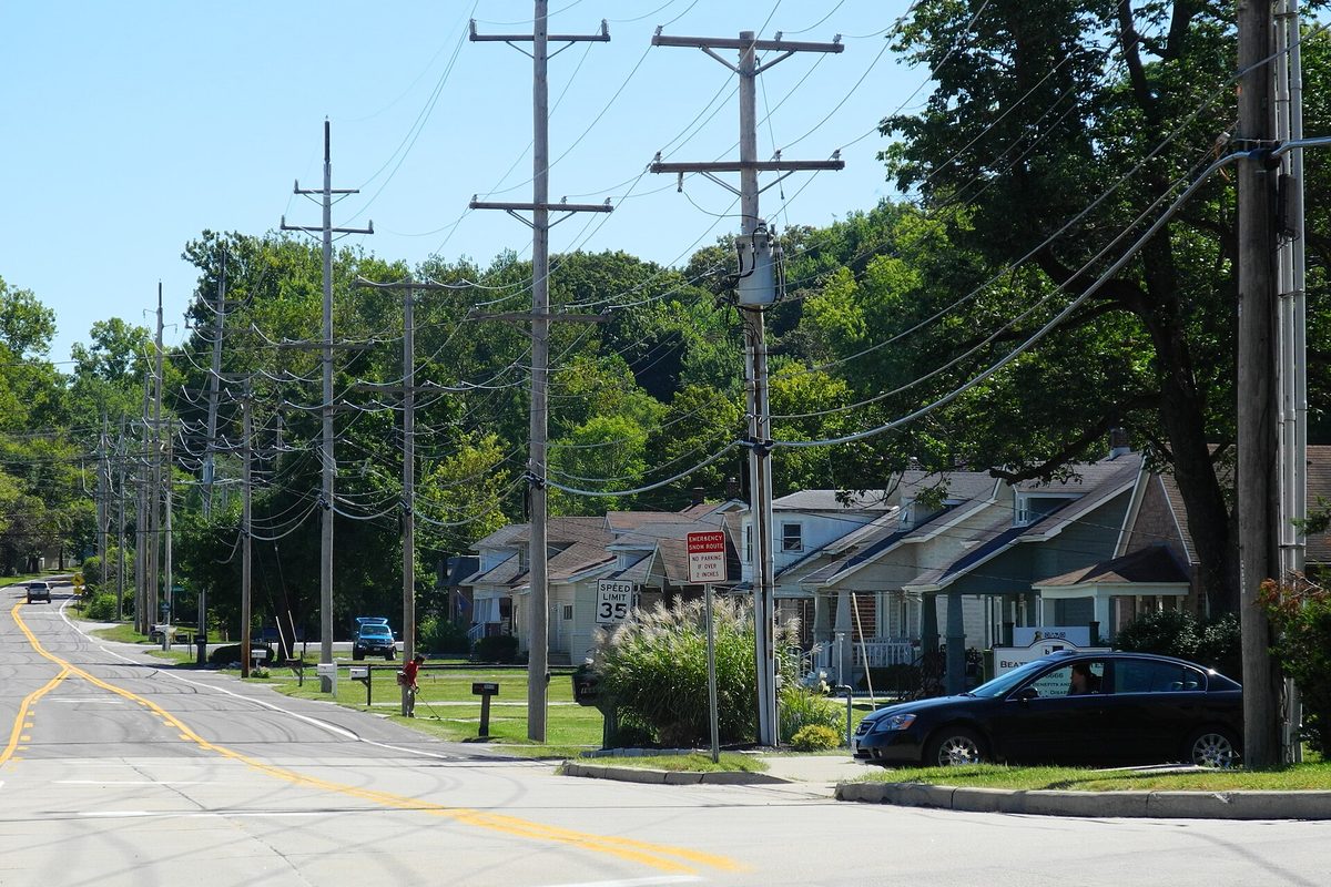 Small houses and utility poles along Chesterfield Airport Road in the Burkhardt Historic District, with a 35 mph sign and a parked dark sedan