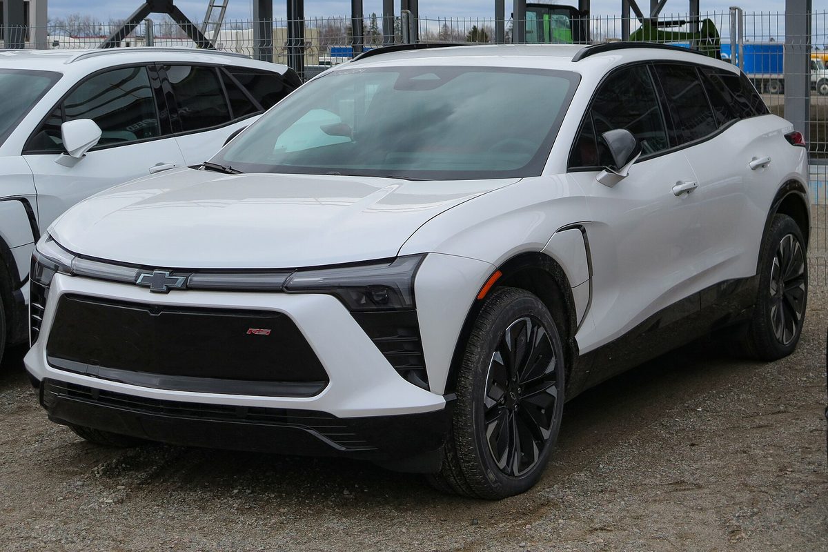 A white 2024 Chevrolet Blazer EV RS on a gravel dealer lot, with another white Blazer EV parked beside it