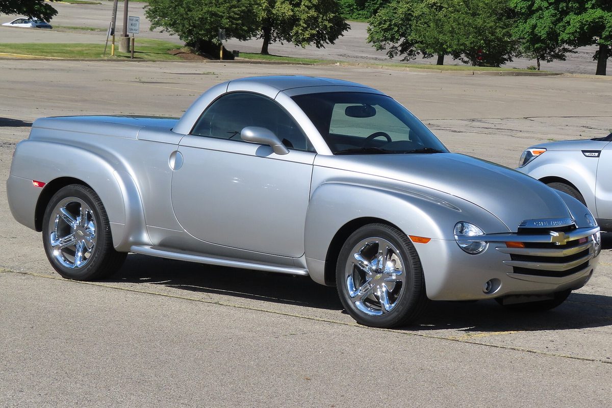 A silver 2005 Chevrolet SSR retractable-hardtop pickup with chrome wheels, parked in an open lot with trees behind it