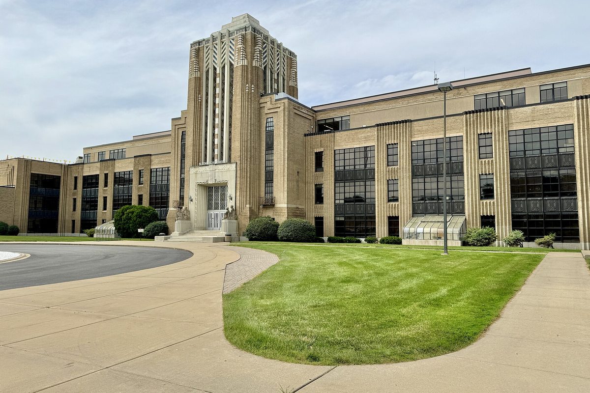 The Art Deco limestone tower and wings of Bloom High School in Chicago Heights, with a green lawn and a curving concrete walkway in front