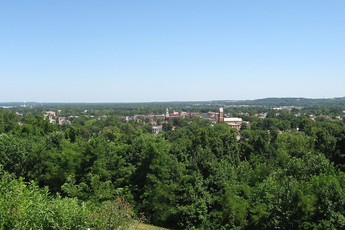 Chillicothe seen from the southwest at the edge of Grandview Cemetery, with church towers and rooftops rising above a sea of green treetops