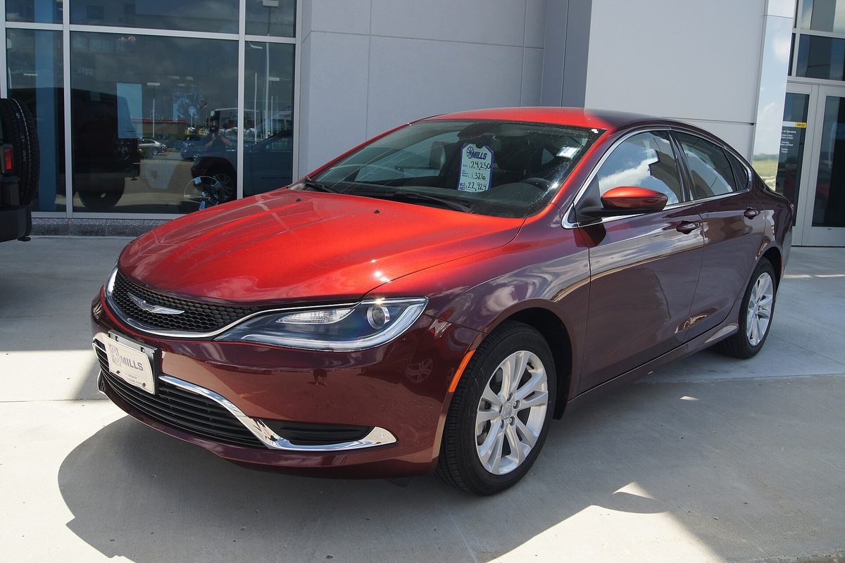 A dark red 2015 Chrysler 200 sedan parked on a dealer lot with a price sticker in the windshield
