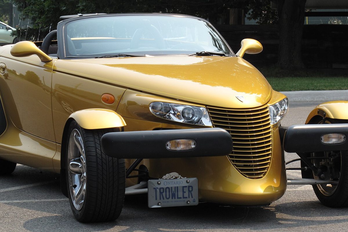 Front of a gold Chrysler Prowler roadster with the top down, showing its vertical-bar grille, pod headlights and separate front bumpers