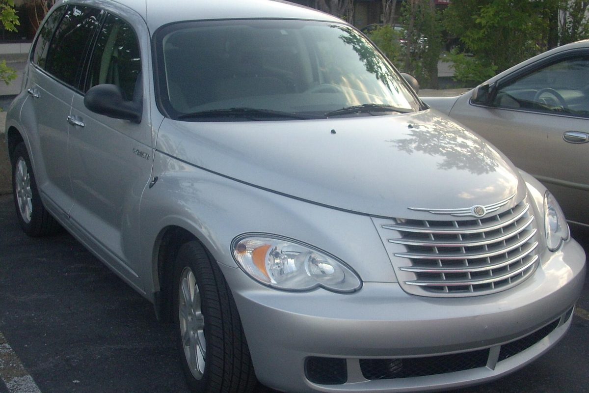 A silver 2006-2009 Chrysler PT Cruiser with a chrome bar grille, parked next to a beige sedan