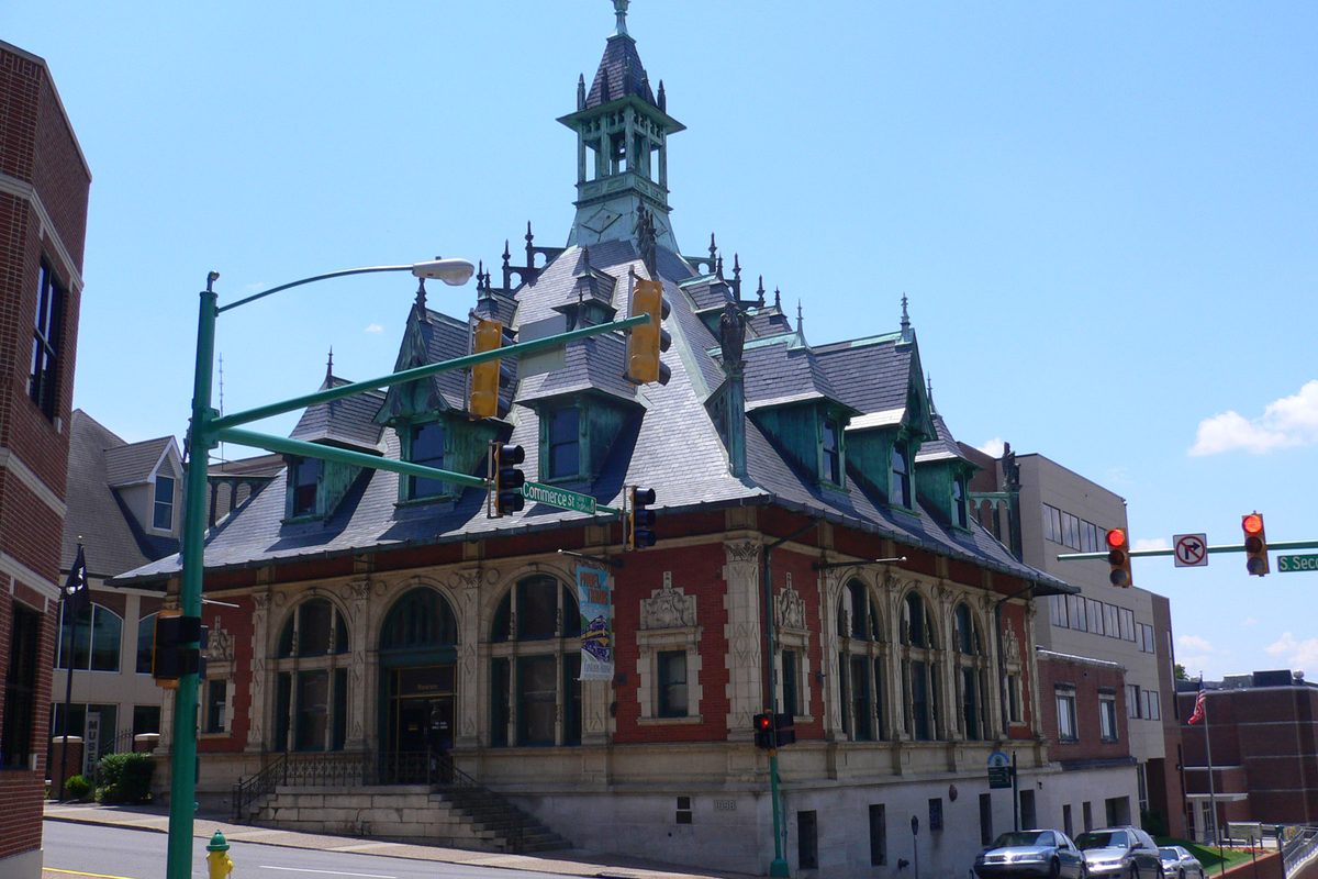 The Clarksville Museum and Cultural Center, an ornate red-brick and stone building with a slate mansard roof and green cupola, beside a traffic signal