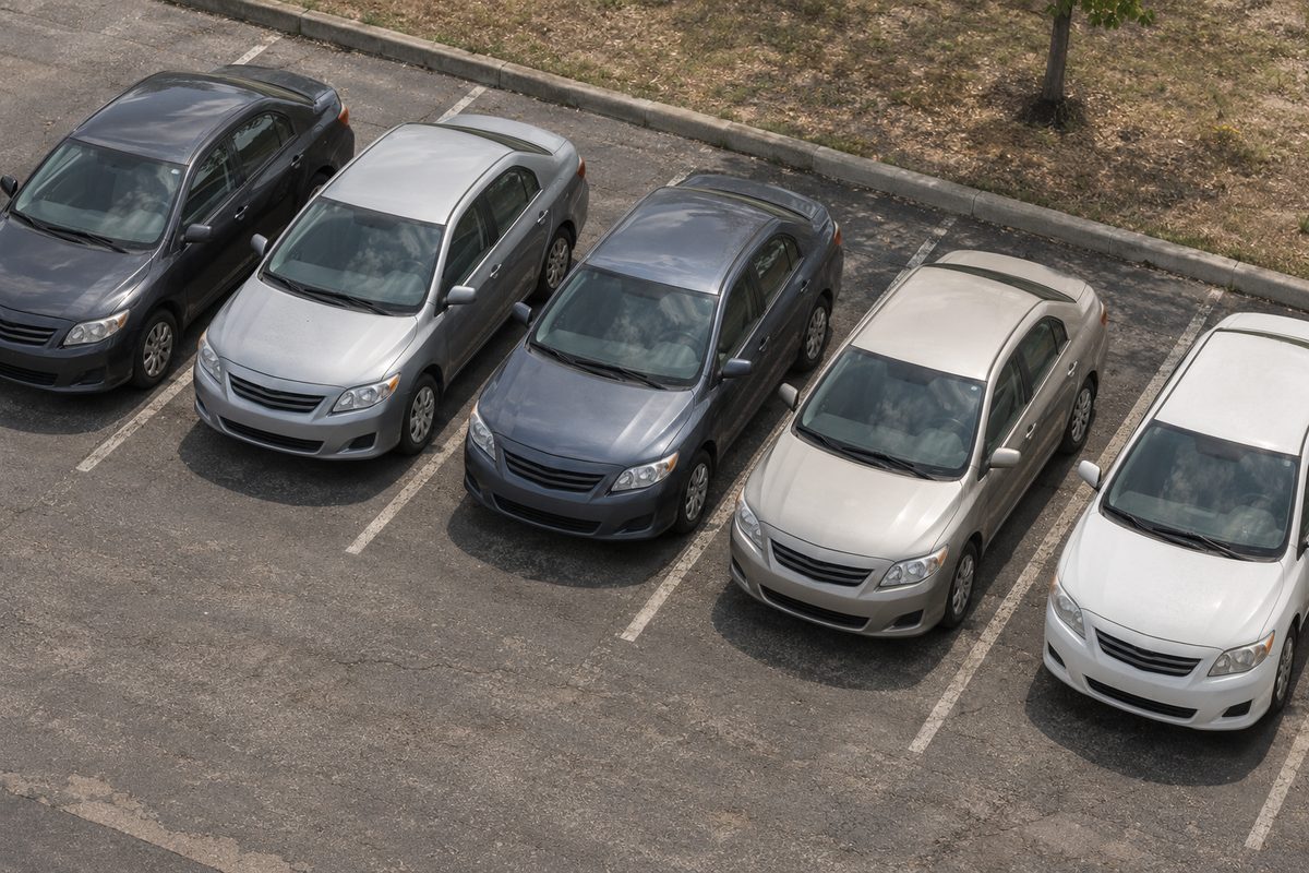 Five silver, gray and white sedans parked side by side in a parking lot, seen from above