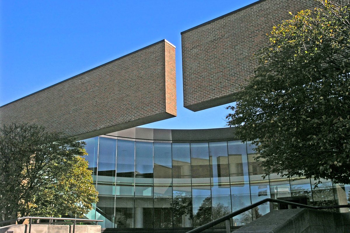 Columbus City Hall, two long brick wings reaching toward each other above a curved glass front, against a deep blue sky