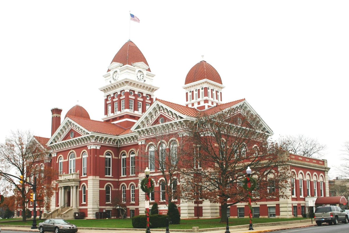 The old Lake County Courthouse in Crown Point, a red brick building with white trim, a clock tower and red domes, with wreaths on the lamp posts