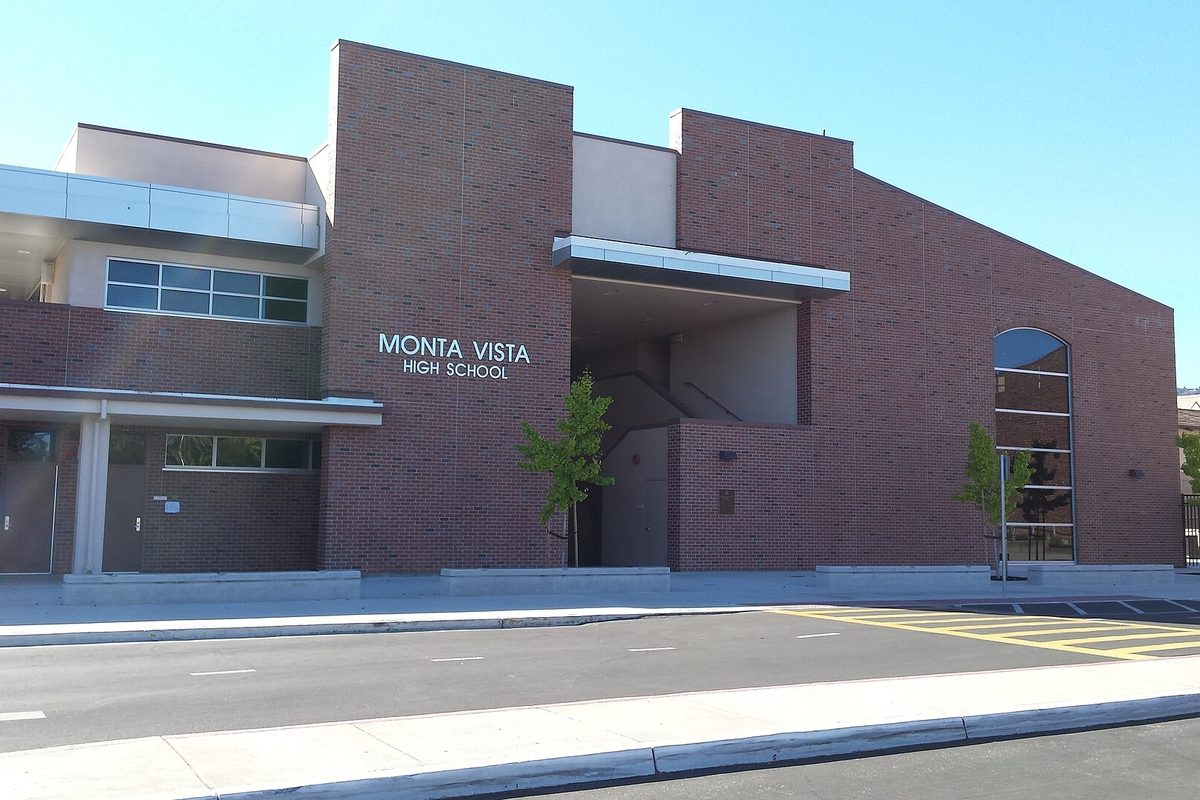 The red brick front of Monta Vista High School in Cupertino, with a young tree by the entrance and a clear blue sky