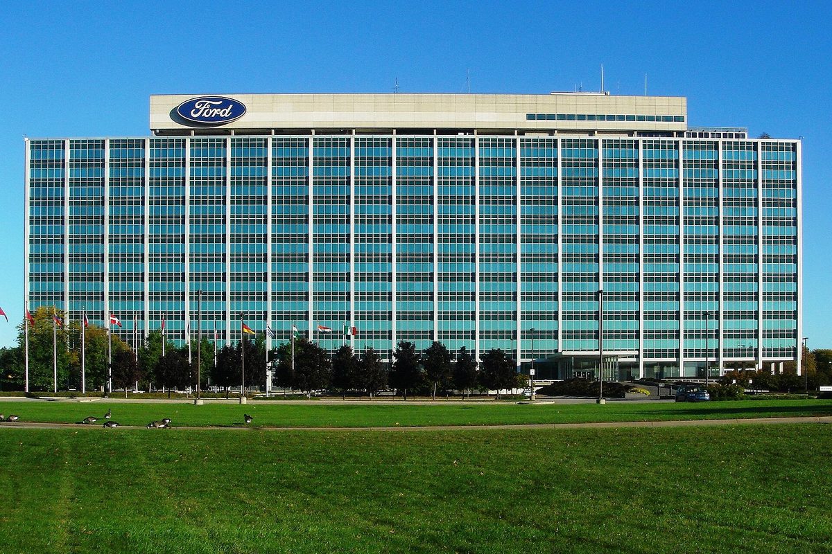 The Ford Motor Company headquarters in Dearborn, a long blue-glass office tower known as the Glass House, behind a wide green lawn