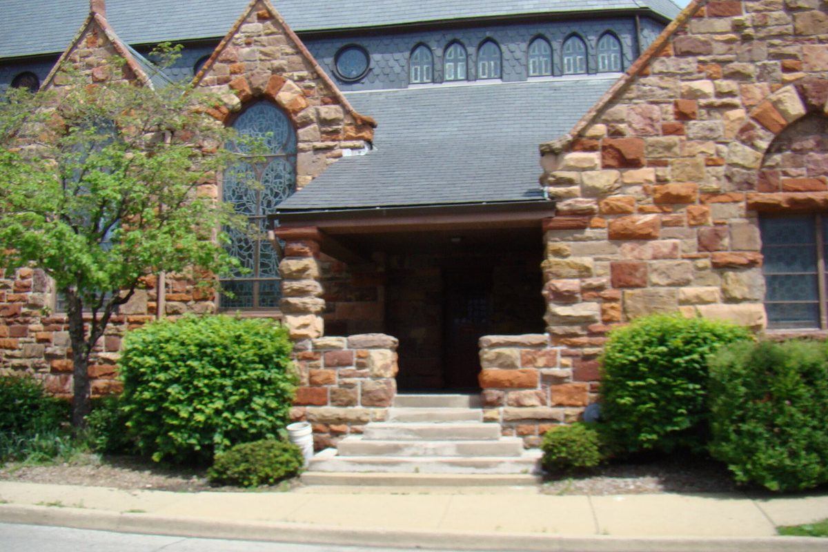 Stone steps leading up to the arched entrance of St. John's Episcopal Church on West Eldorado Street in Decatur, with rounded shrubs on both sides
